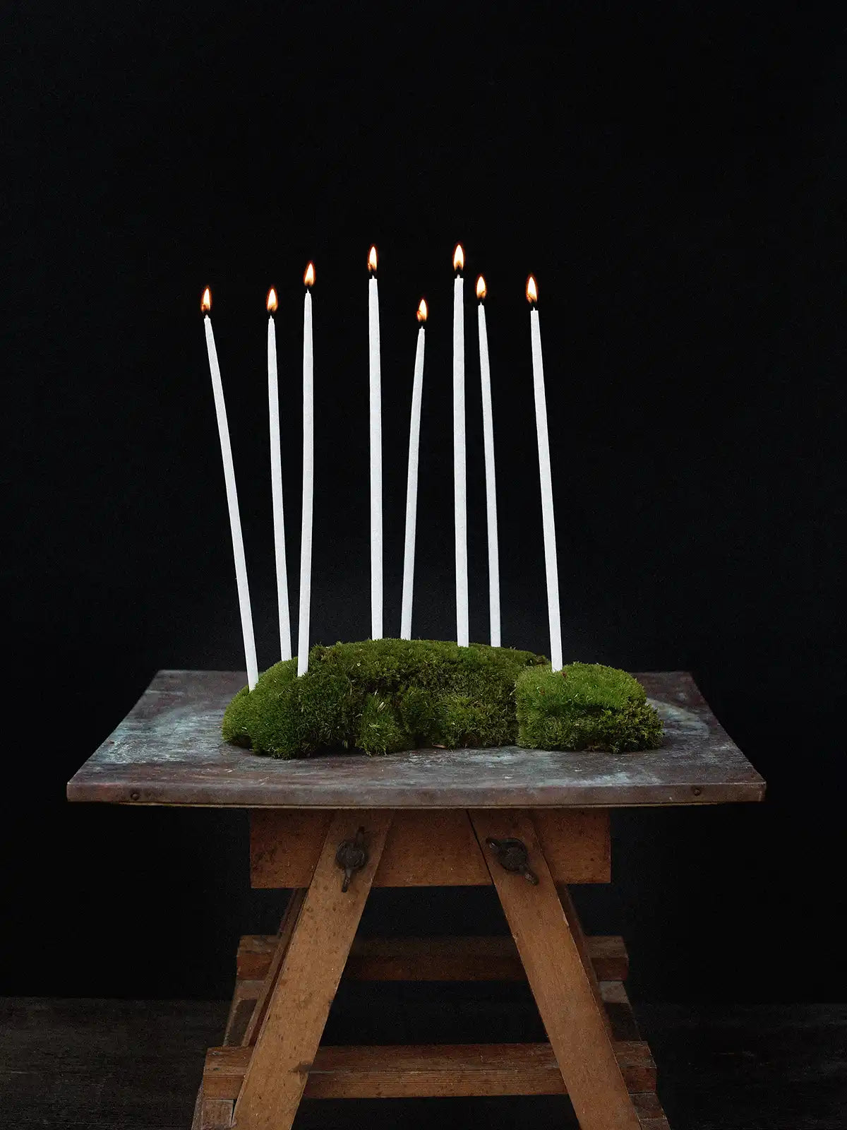 Smala ljus i mossa på ett bord